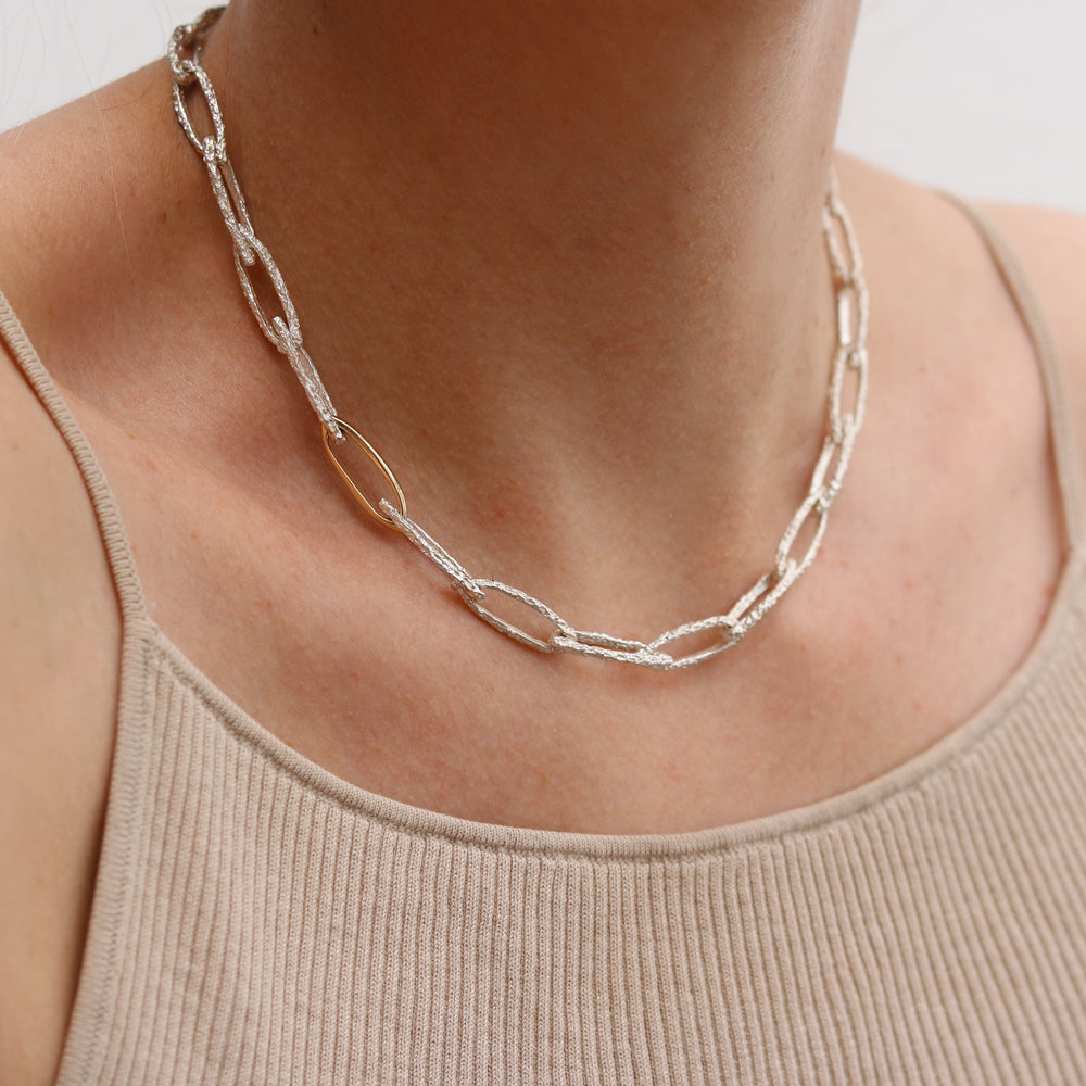 silver and gold textured organic necklace worn by model 