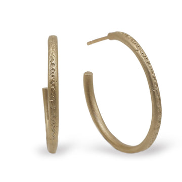 yellow gold hoop earrings with words etched on a white background