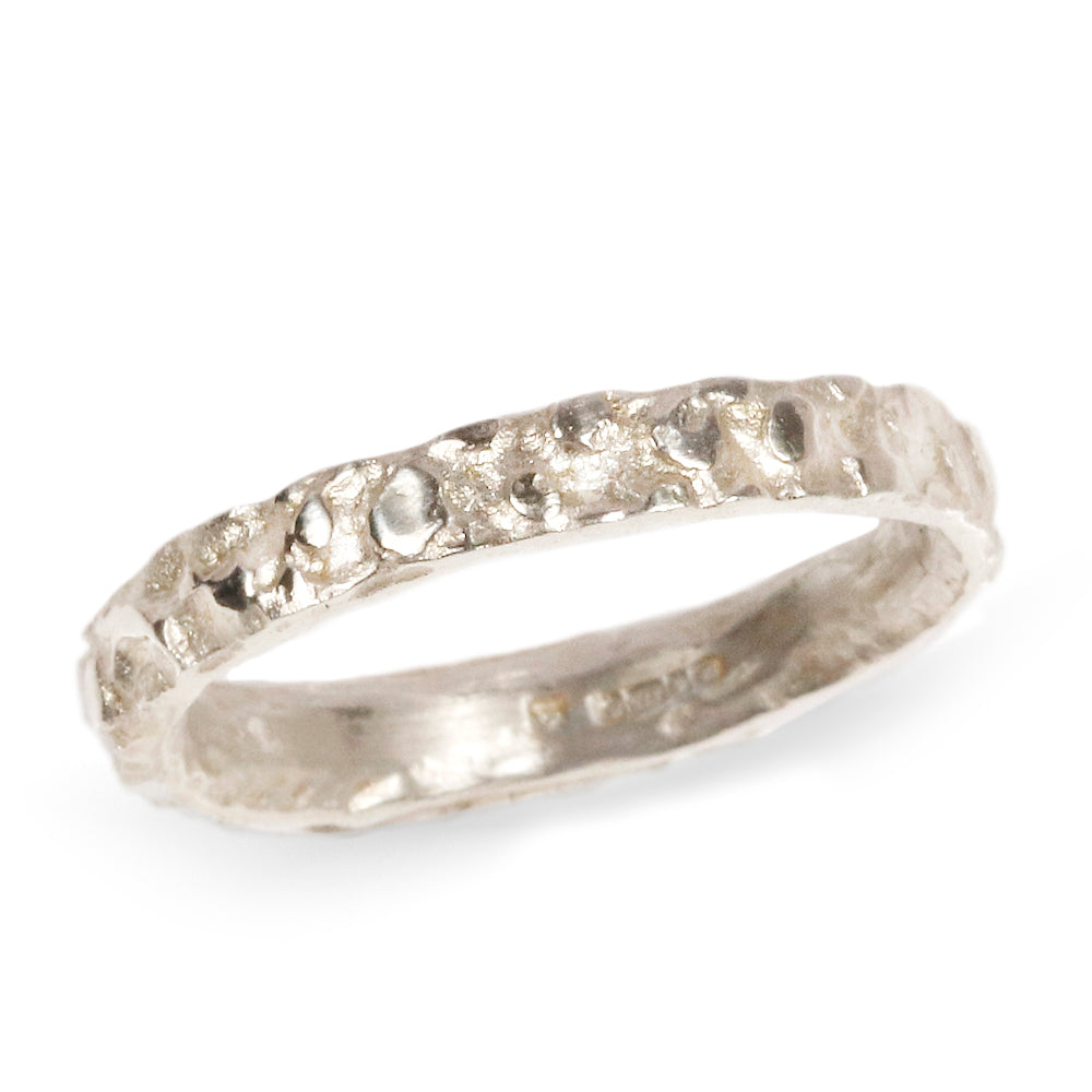 A narrow 9ct white gold wedding band with molten texture on a  white background