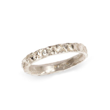 A narrow 9ct white gold wedding band with molten texture on a  white background
