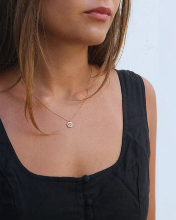 Close-up of a person wearing a delicate necklace with a small pendant.