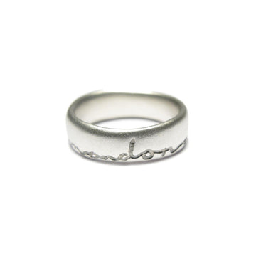 Silver wedding ring with 'and on' etched in black. Displayed on a white background
