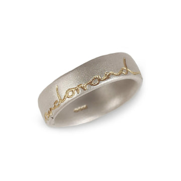 Silver wedding ring with 'and on' etched in gold. Displayed on a white background