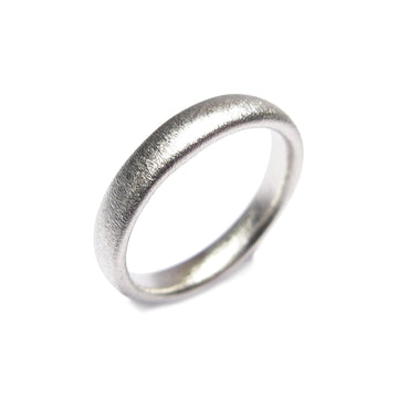 A narrow Platinum wedding ring with matt finish on white background