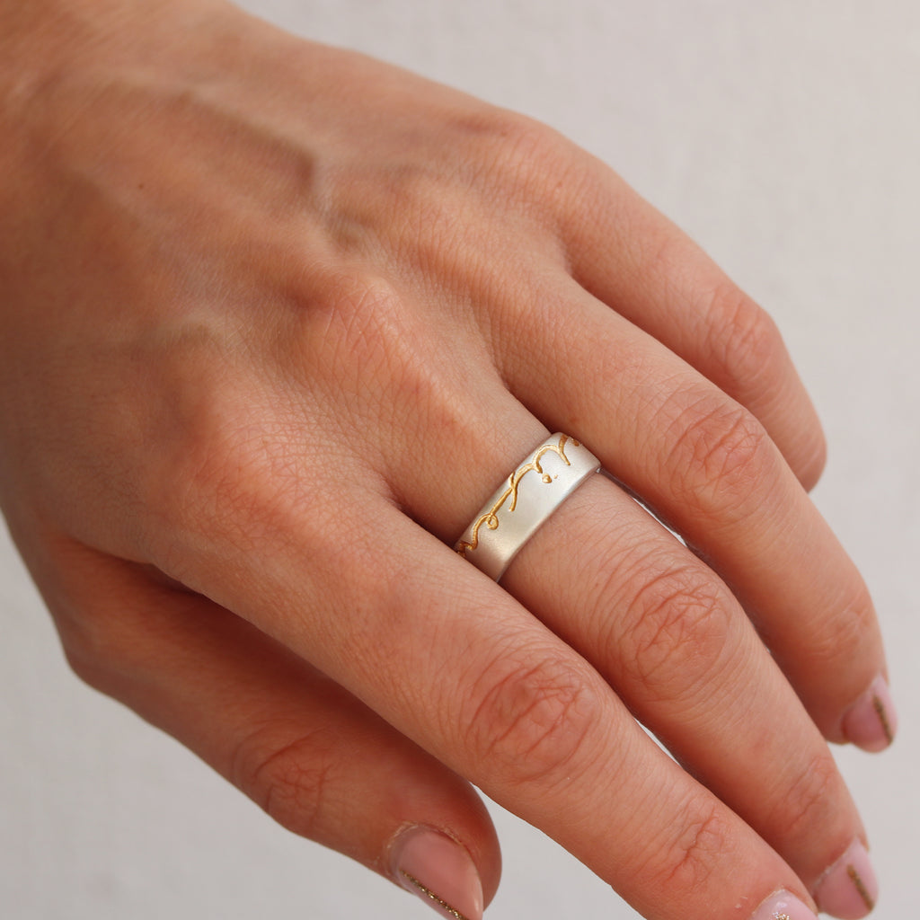 Modern Silver Ring etched with wisdom of life in yellow gold etching worn on a middle finger