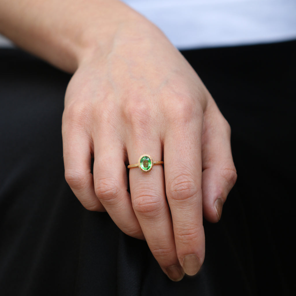 Textured Yellow Gold Ring With a Green Oval Tsavorite Garnet worn on hand 