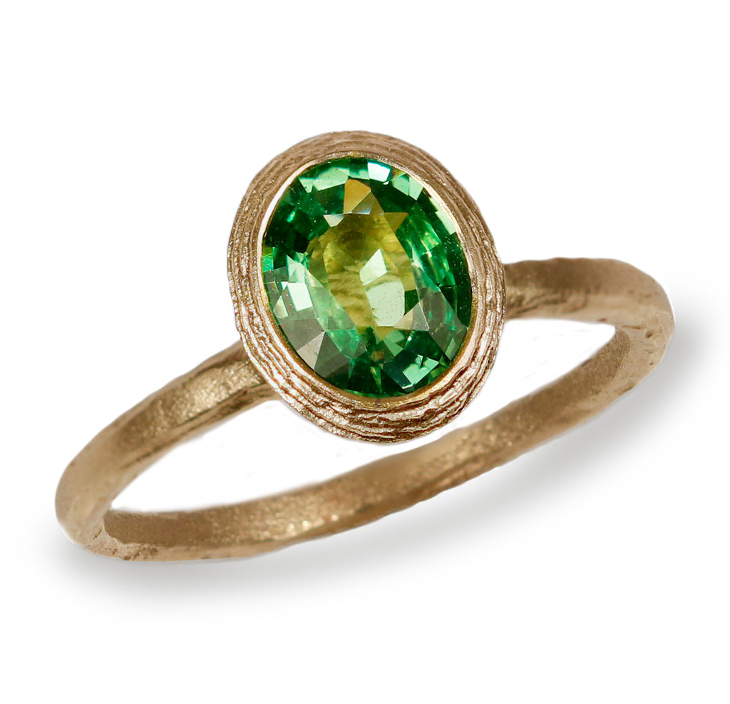 Textured Yellow Gold Ring With a Green Oval Tsavorite Garnet on white background