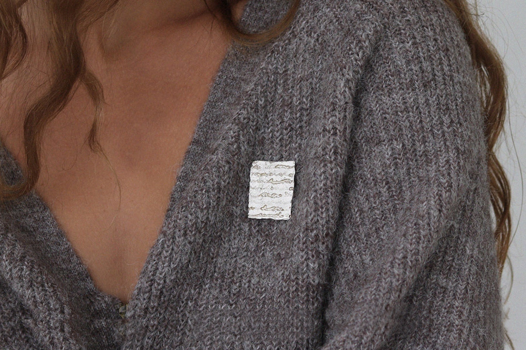 A silver brooch with etched letters