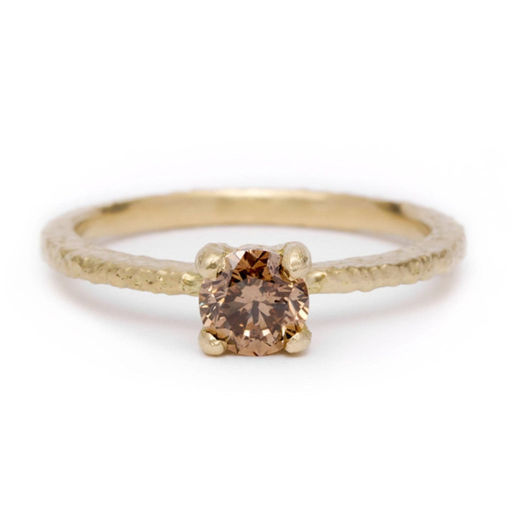 Gold ring with a solitaire champagne diamond on a white background