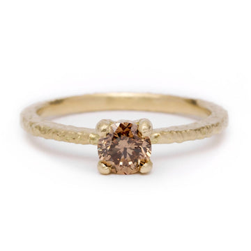Gold ring with a solitaire champagne diamond on a white background