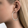 woman with blonde hair wearing large spikey silver hoops in her ear