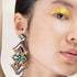 Close-up of a woman wearing a colorful earring with a neutral background