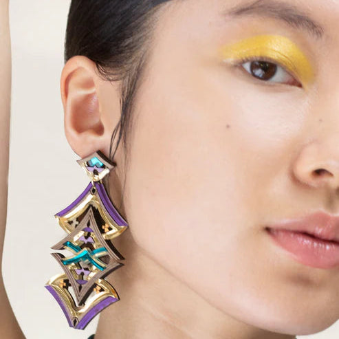 Close-up of a woman wearing a colorful earring with a neutral background