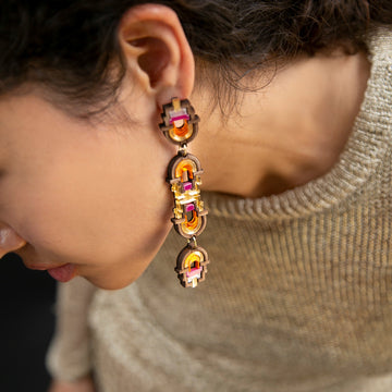 Close-up of a person wearing a decorative earring with gemstones.