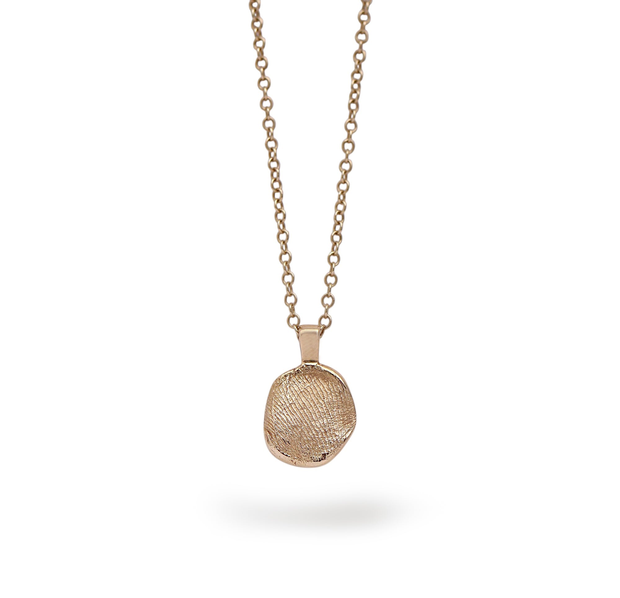 A gold memorial fingerprint necklace with a textured, organic-shaped pendant, suspended against a clean white background with a soft shadow underneath.