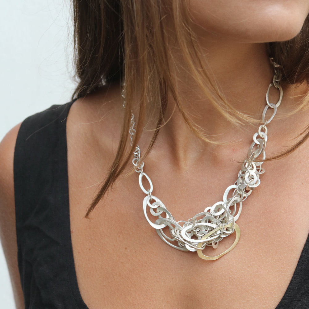 Silver chain necklace worn by a person against a neutral background