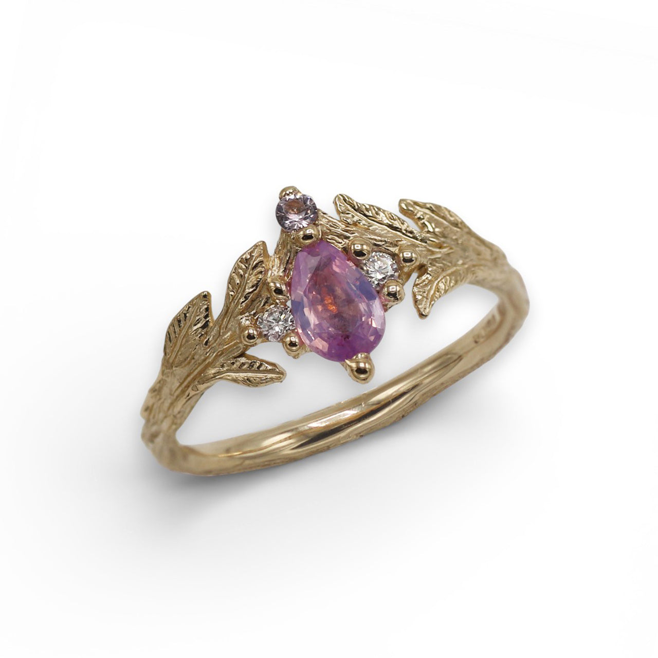 Gold ring with pink Sapphire, diamonds and leaf designs on a white background