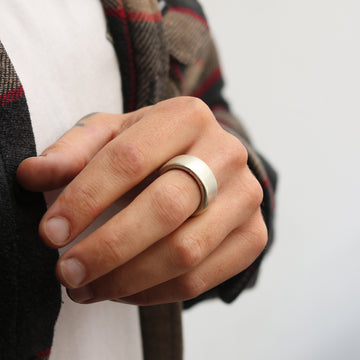 Side view of chunky silver mens ring worn by a male on his middle finger