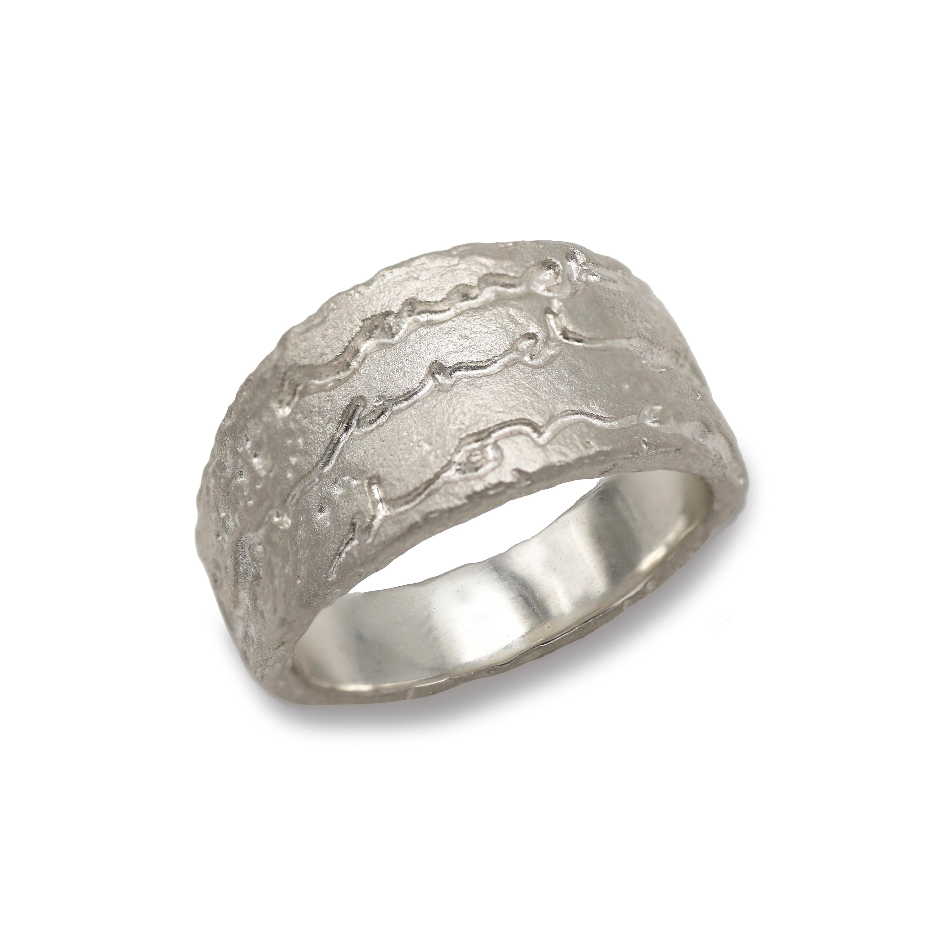 A chunky silver ring etched with the words on and on on a white background. 