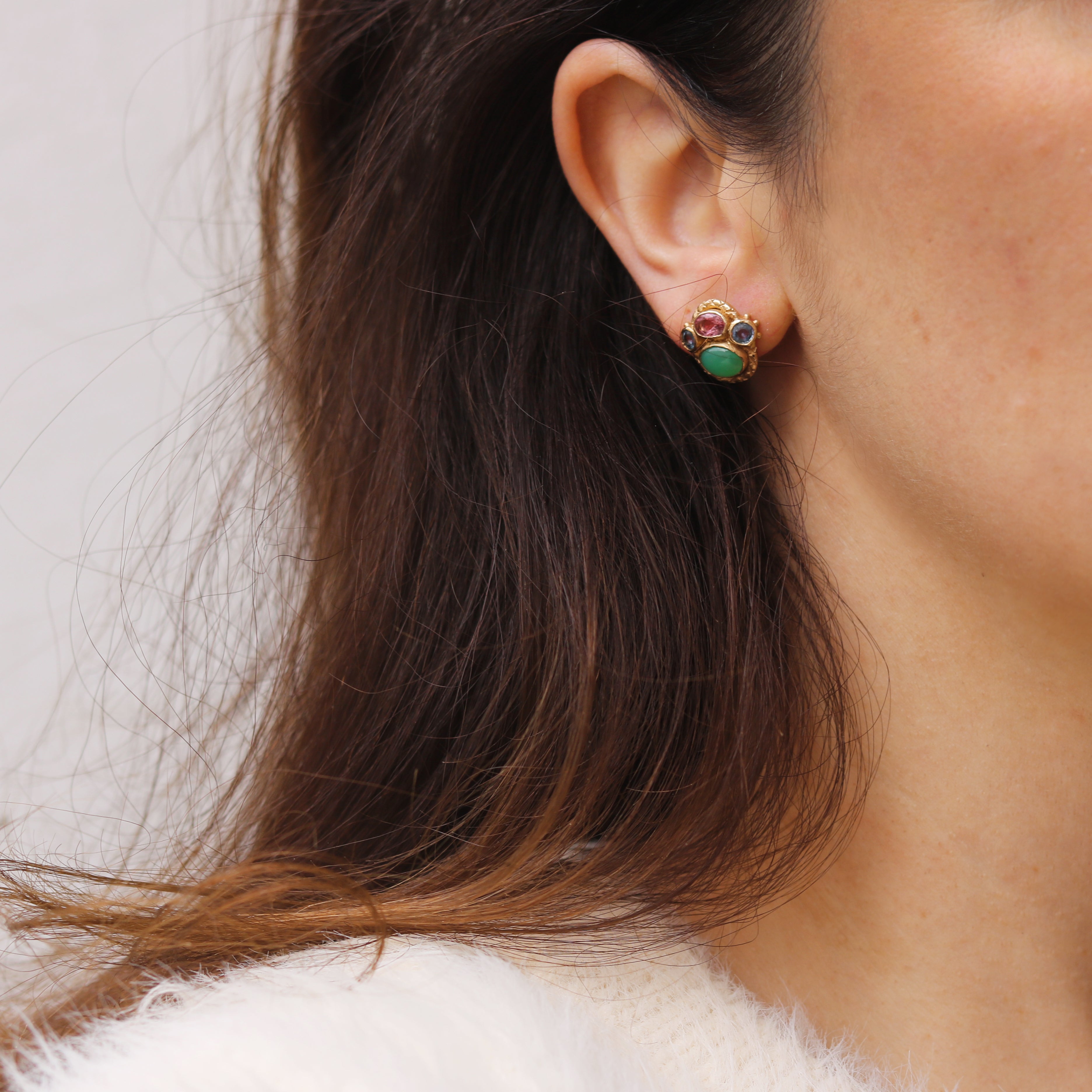 Yellow gold Queenie Earrings by Ciara Bowles with jade, and pink and blue sapphires, worn by woman with dark hair