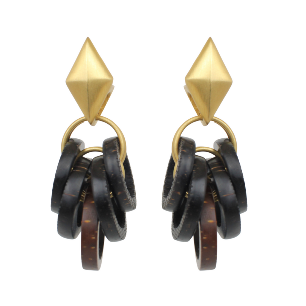Pair of earrings with gold tops and black circular drops, created from laser engraved pine nut kernels on a white background