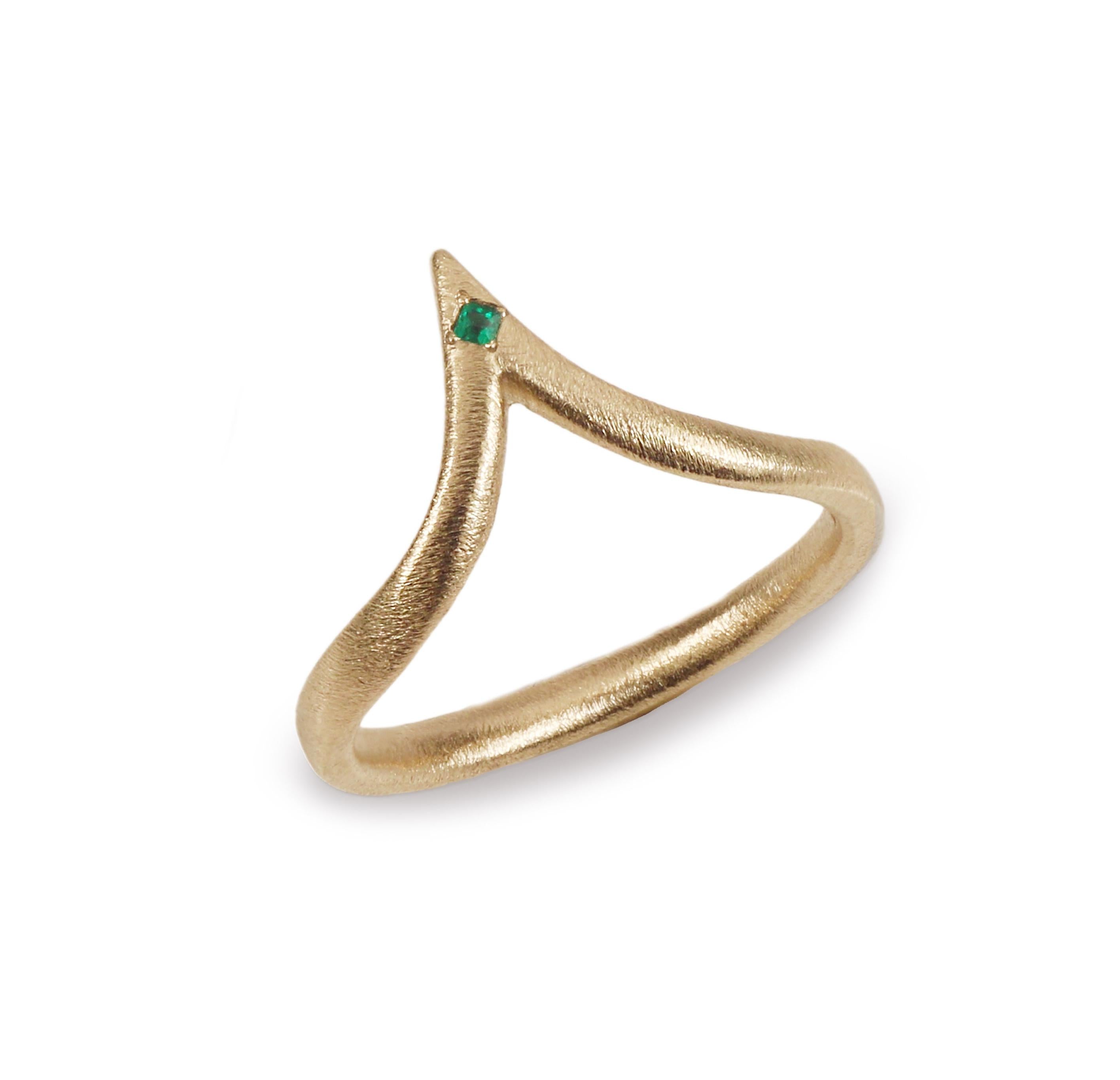 Gold extended wishbone ring with a green emerald on white background 