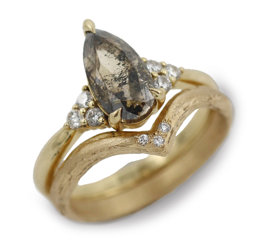 Gold wishbone ring with diamonds and a salt and pepper diamond ring on white background 