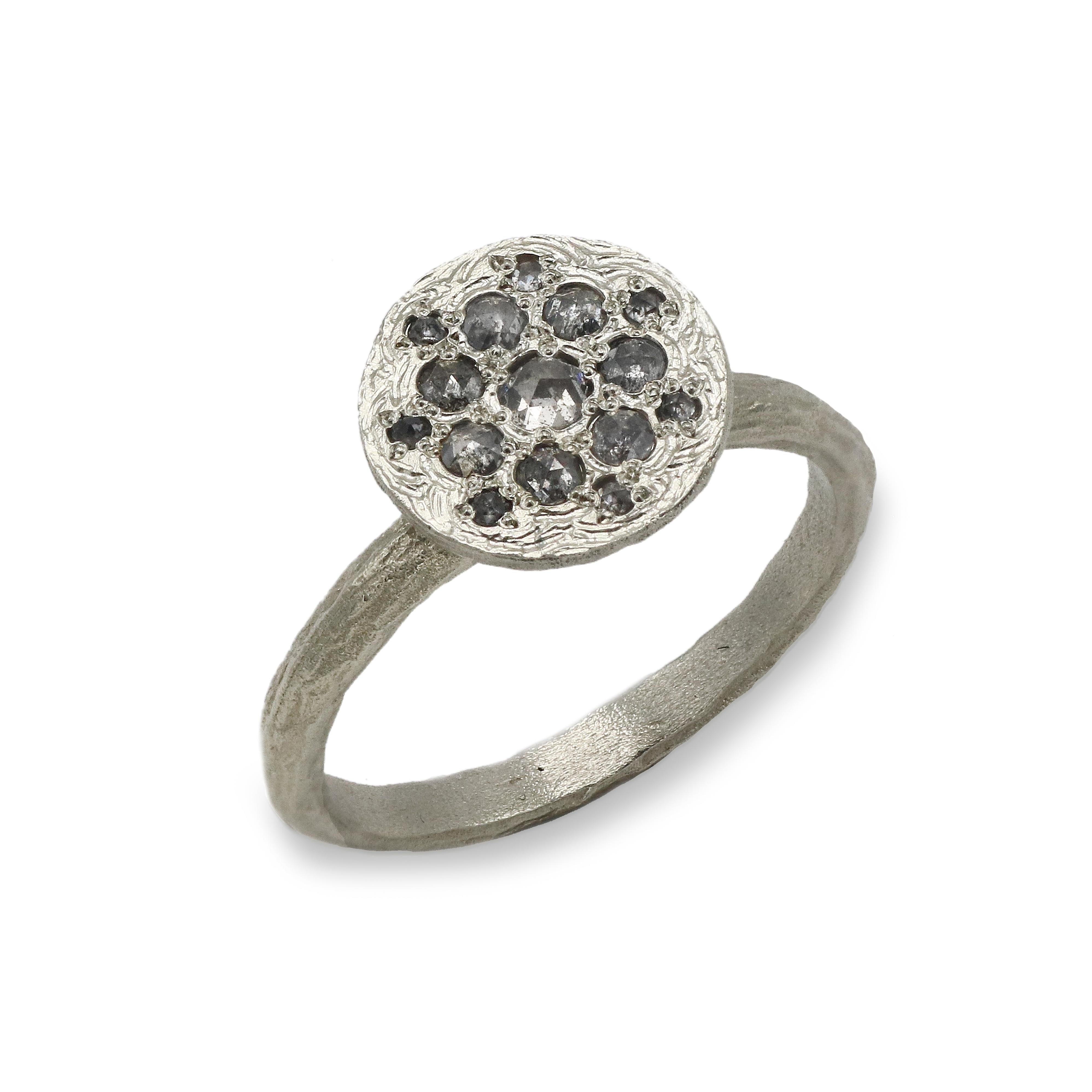 Patterned white gold ring with salt and pepper diamonds on a white background 