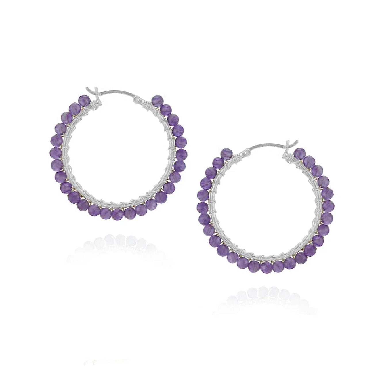 A pair of silver hoop earrings embellished with small purple beads, displayed on a clean white background with a soft reflection below.