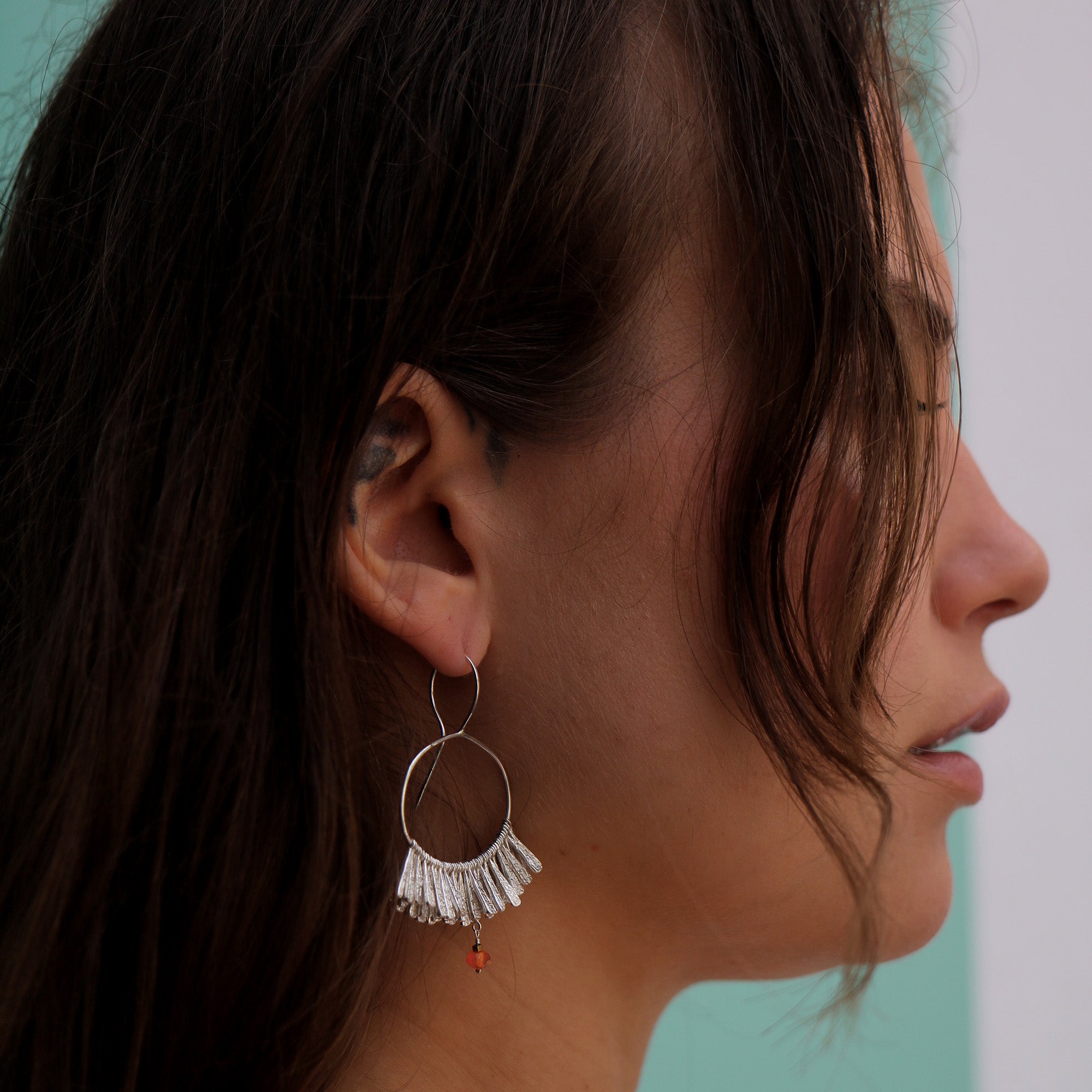 Silver fan earrings worn by a woman with dark hair