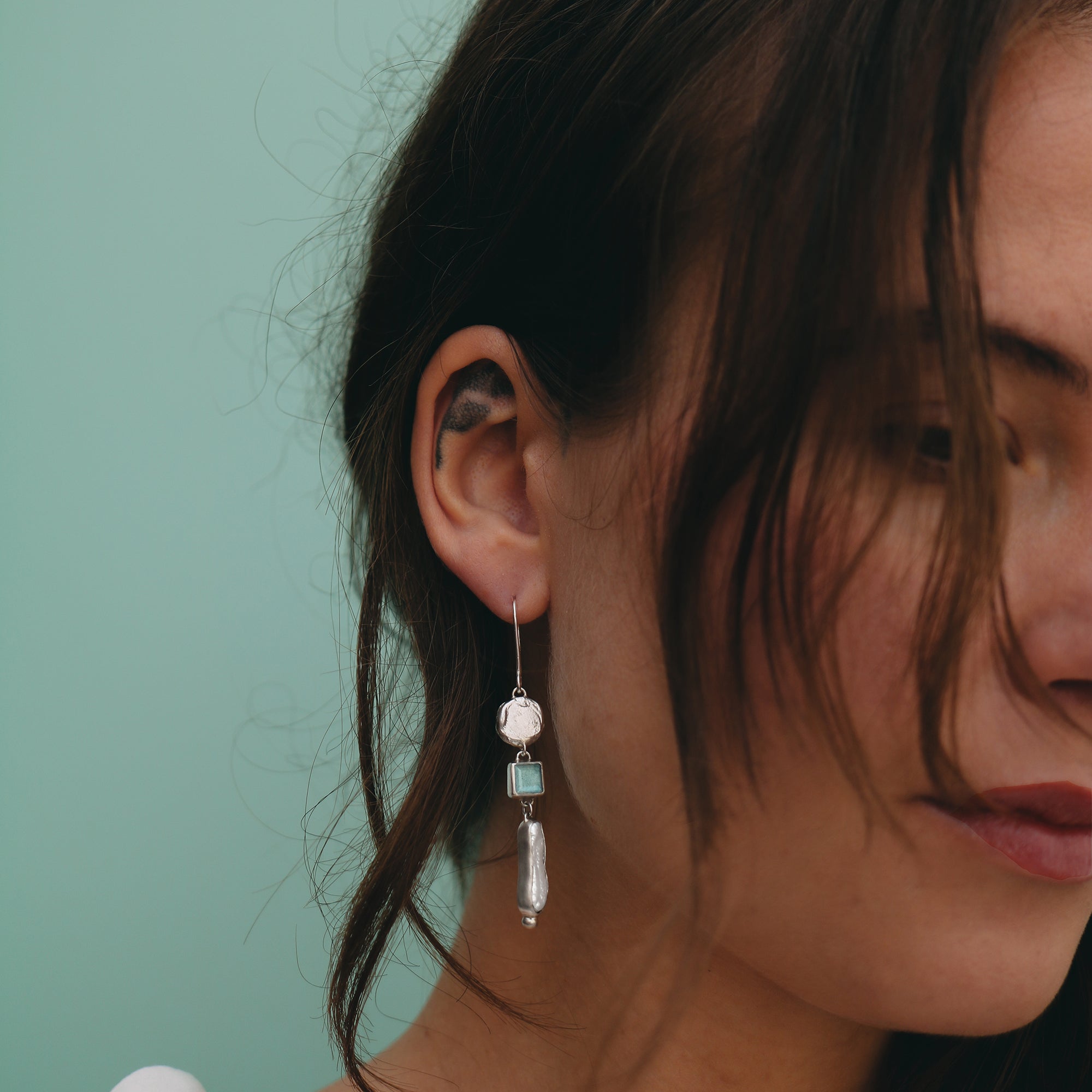 Close-up of a woman wearing an earring with a green background