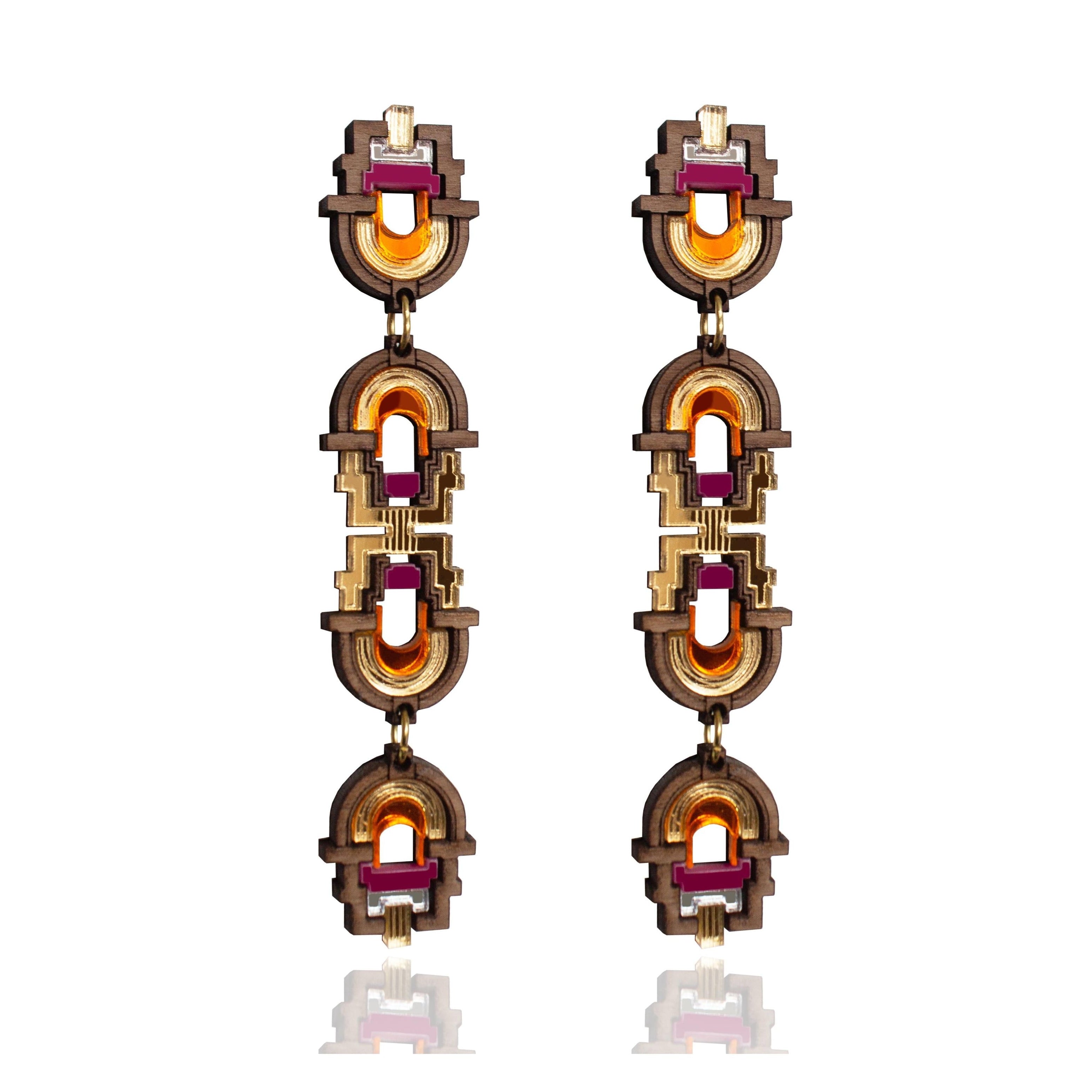 Pair of ornate earrings with gold and red accents on a white background