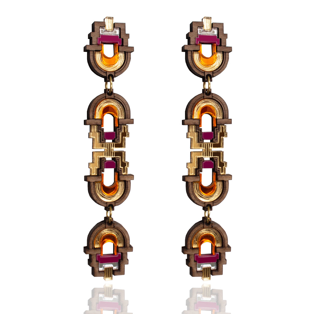 Pair of ornate earrings with gold and red accents on a white background