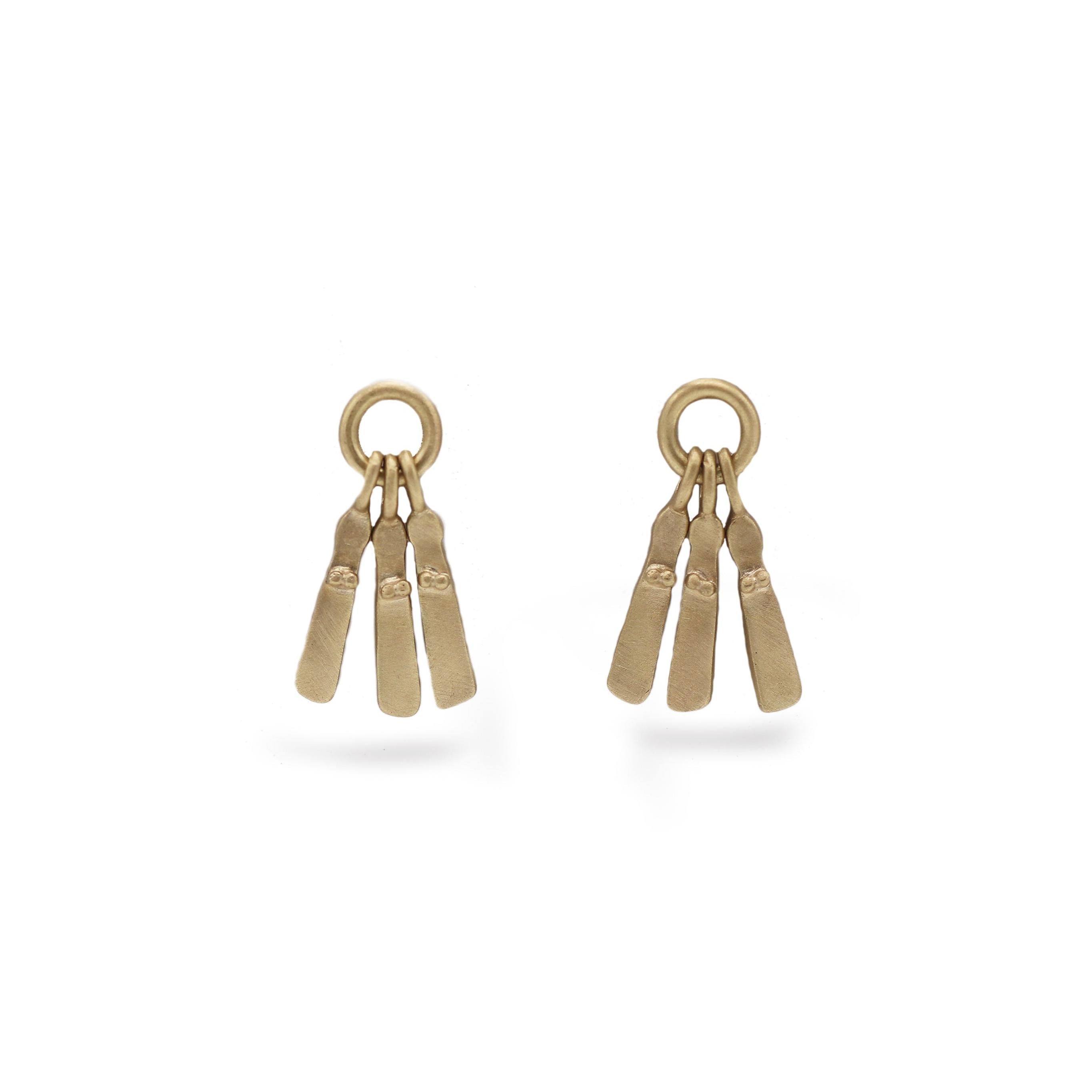 A pair of yellow gold mini Sibyl earrings with a brushed matt finish, hanging from a mini silver hoop. On a white background