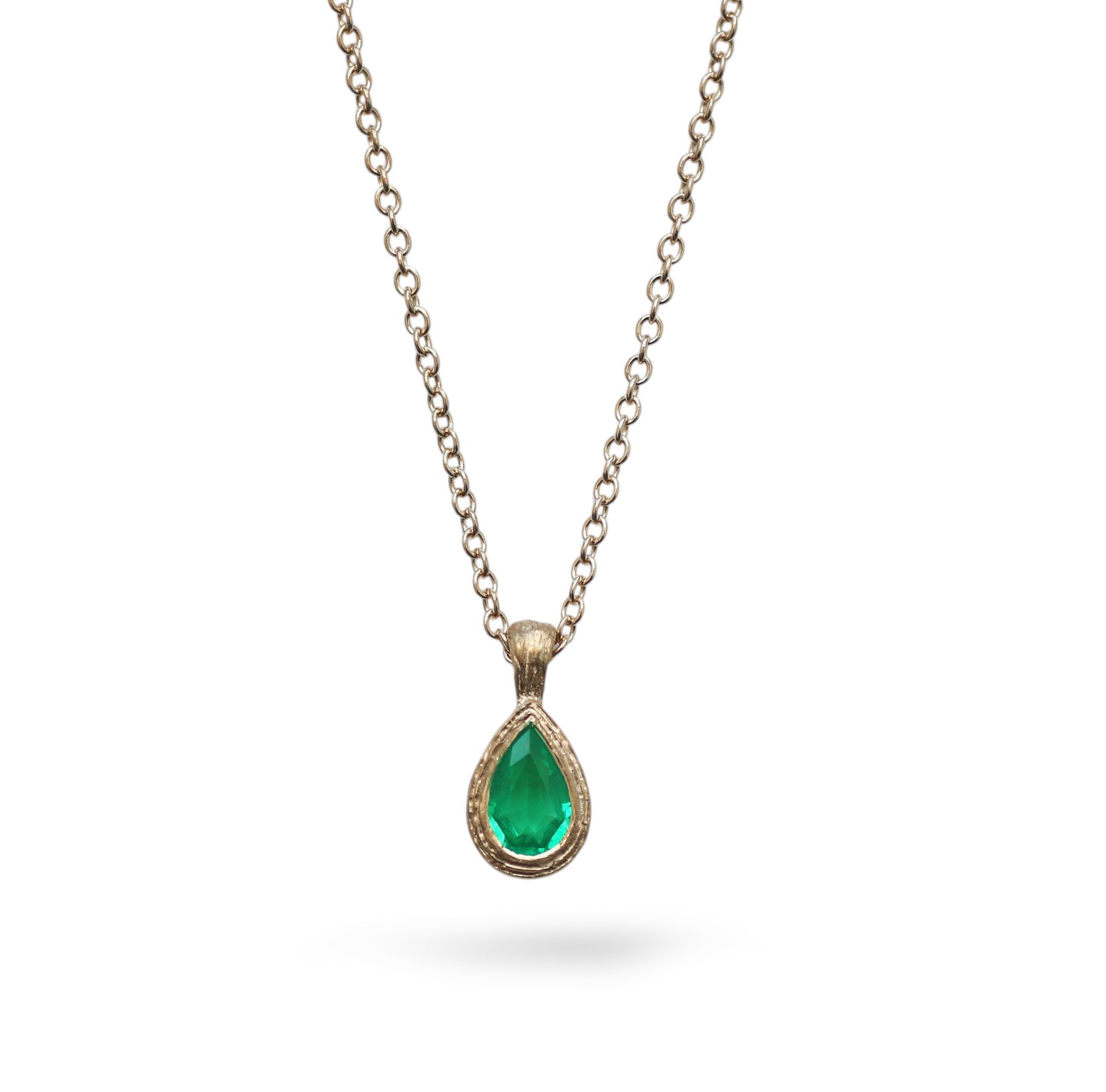 pear cut emerald in yellow gold pendant on a white background 