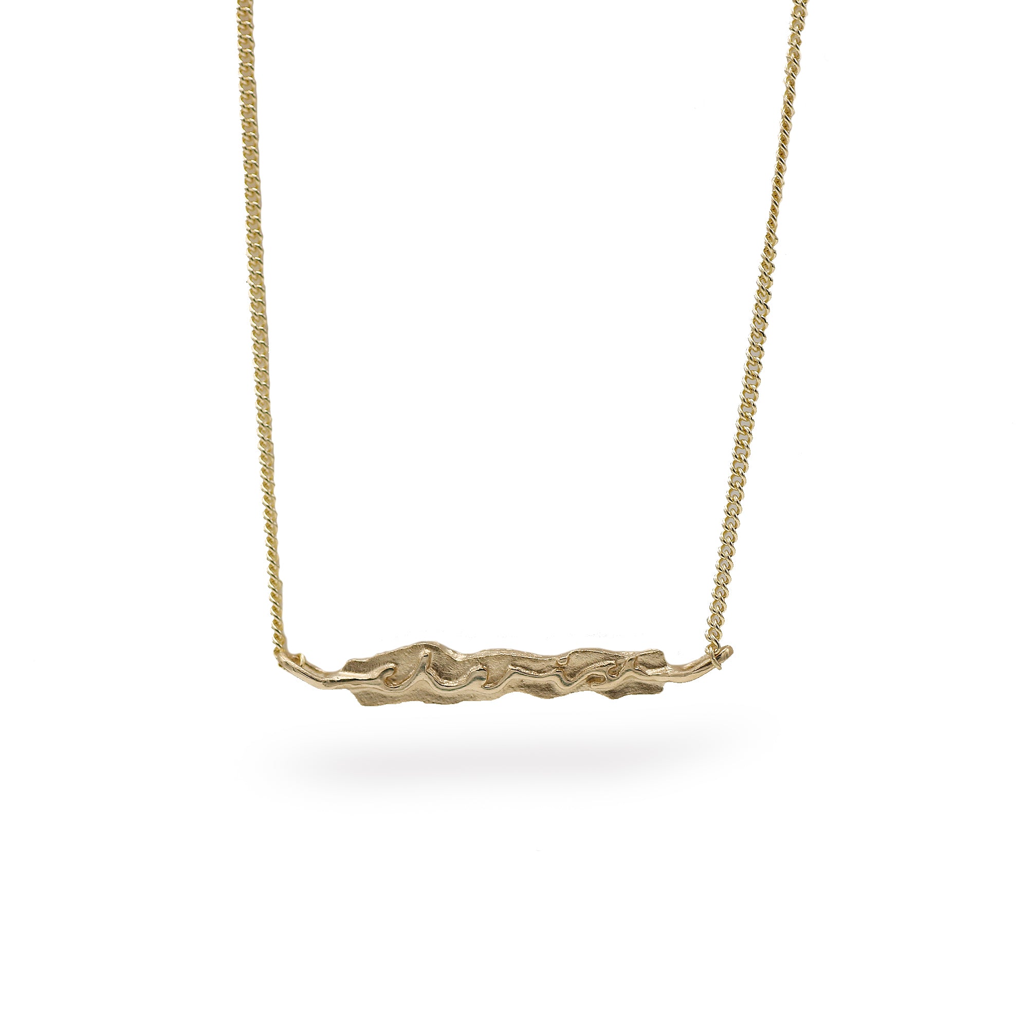 A gold necklace featuring a textured, organic-shaped horizontal bar pendant suspended from a fine gold chain, set against a plain white background.