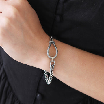 Silver bracelet on a wrist with a black dress in the background