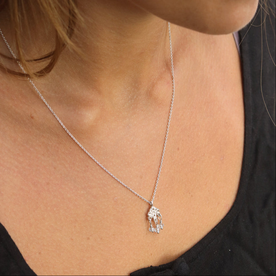 Woman wearing silver textured pendant with aquamarine beads