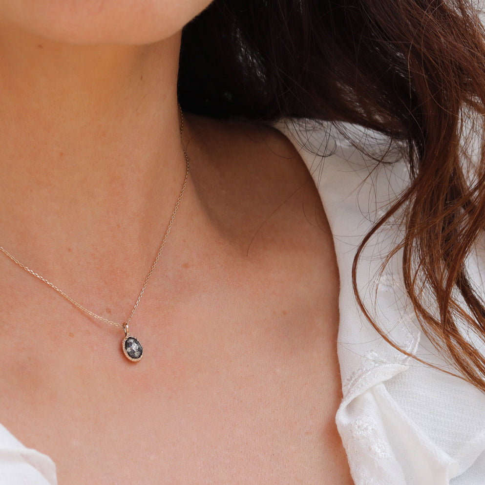 Rusty Though oxidised pendant with Diamonds in 10k yellow gold worn by a woman with a white shirt