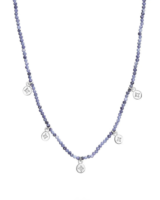 Blue beaded necklace with small silver pendants on a white background