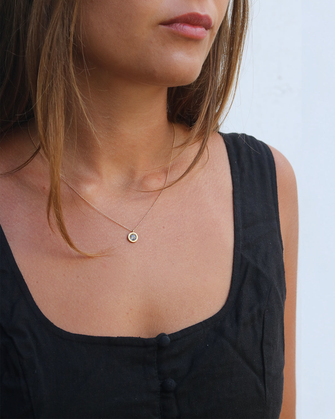Close-up of a person wearing a delicate necklace with a small pendant.