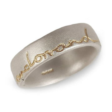 Silver wedding ring with 'and on' etched in gold. Displayed on a white background