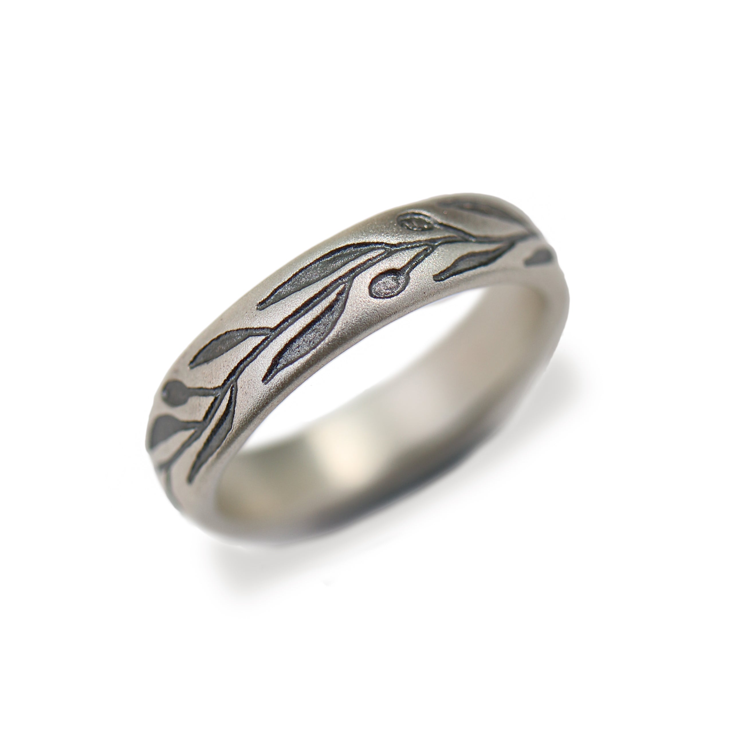 A silver-toned metal ring featuring an engraved olive branch design with leaves and olives, shown on a clean white background.