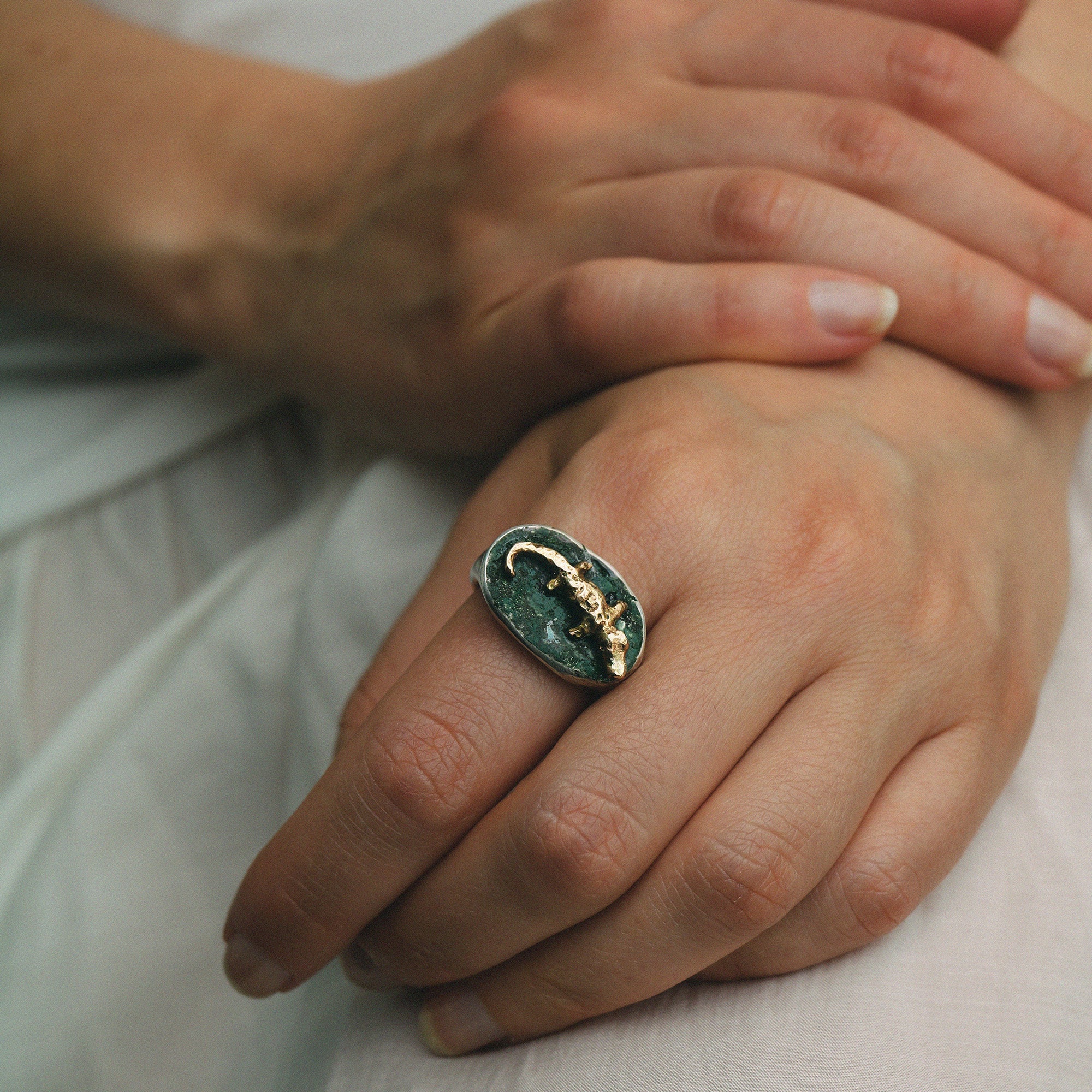 Close-up of a hand wearing a ring with a unique design on a light background