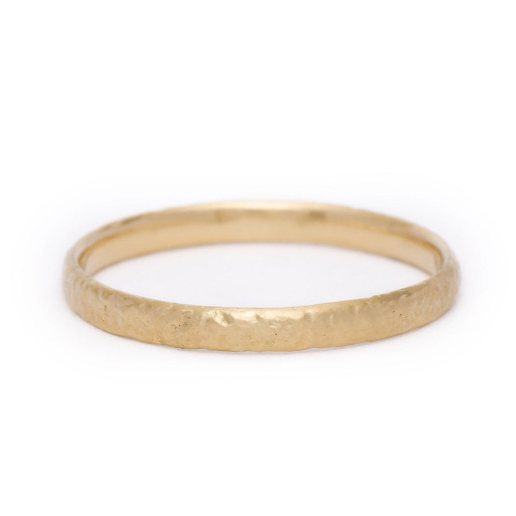 Gold ring with a textured surface on a white background