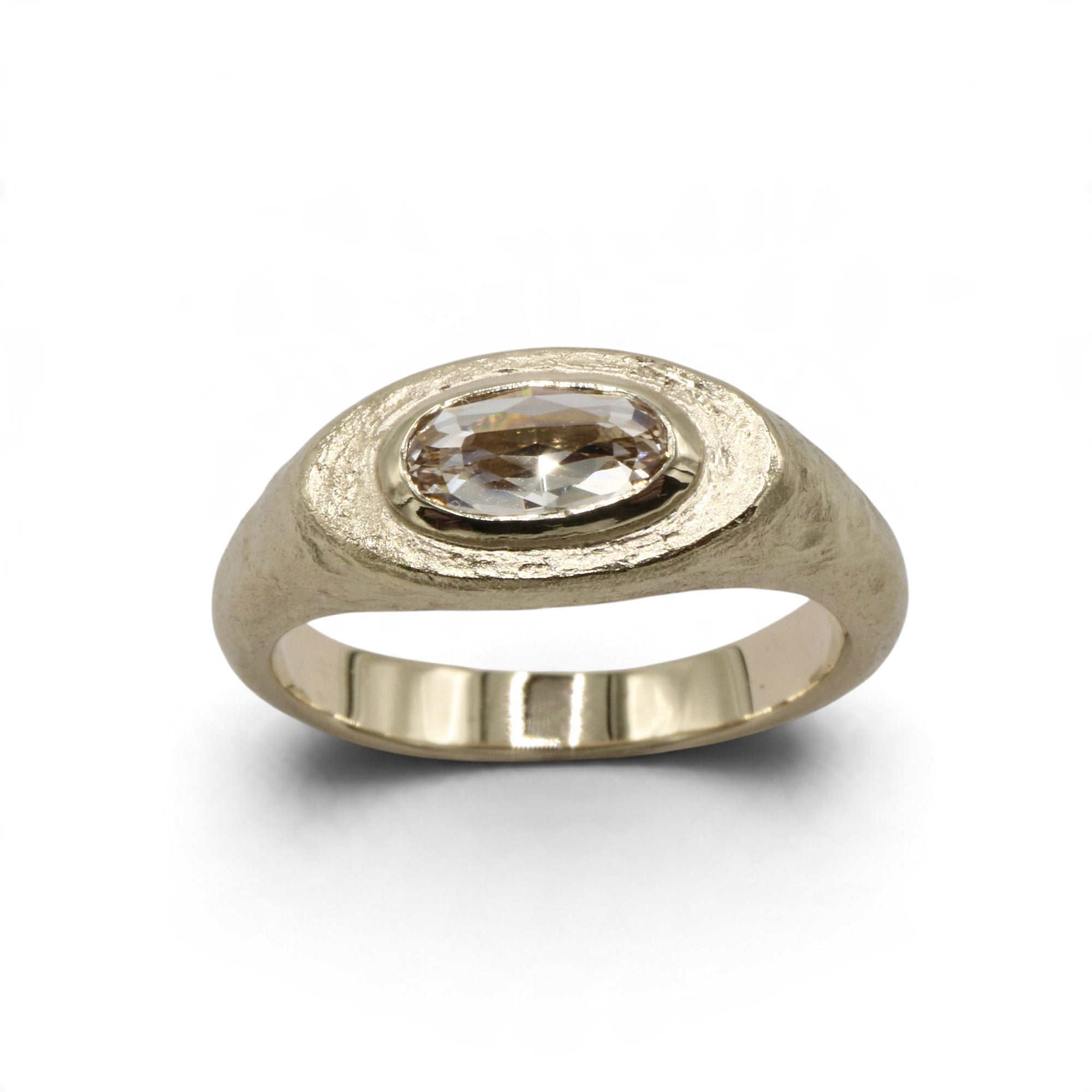 Textured white gold ring with oval diamond on a white background. 