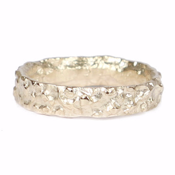 Yellow gold wedding ring with molten texture on white background
