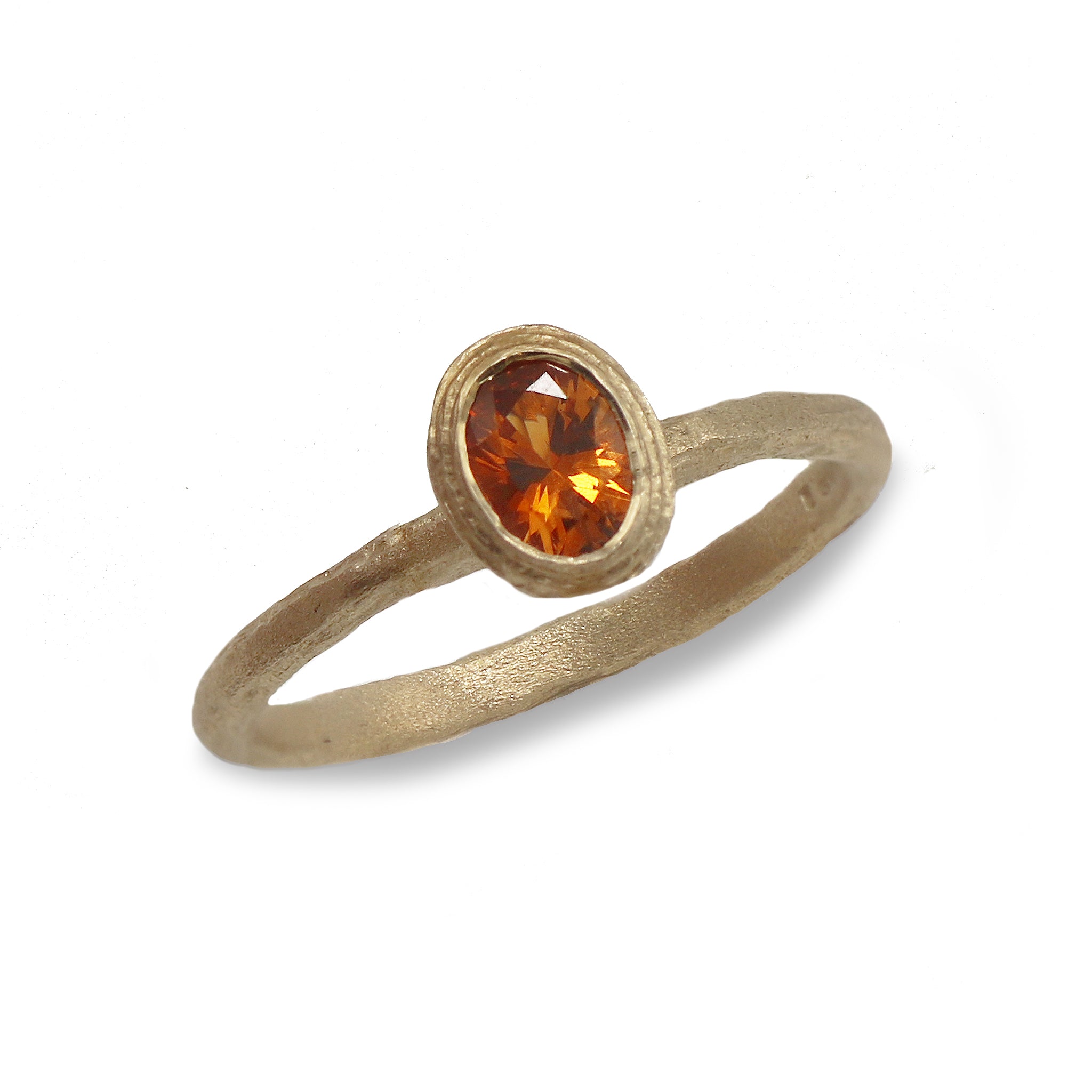 yellow gold ring with an oval orange sapphire on a textured band 