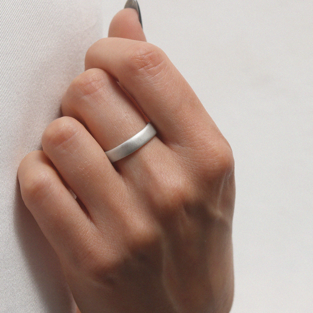 plain silver ring with a matt finish worn on a ladies hand