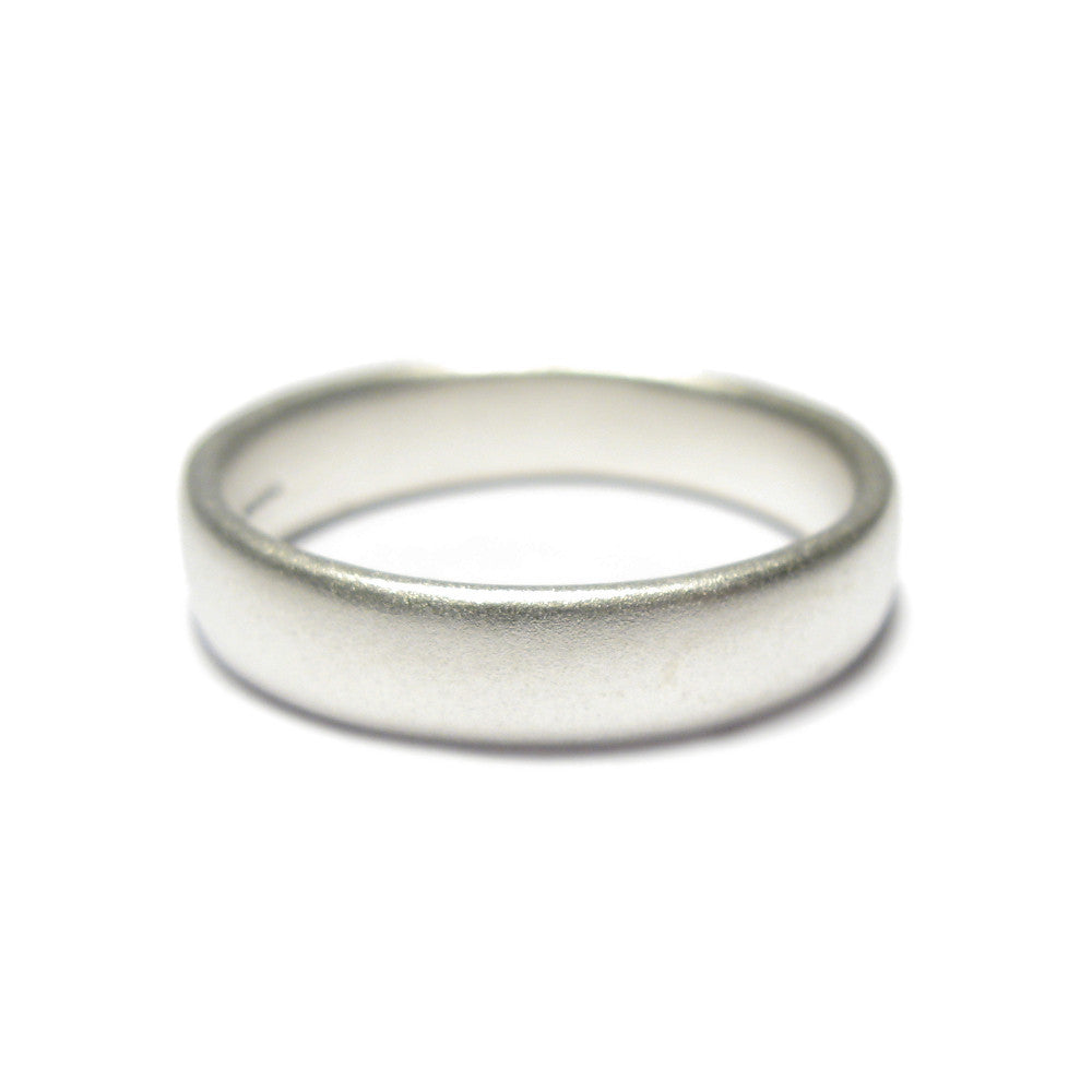 A plain silver wedding ring with a matt finish on a white background